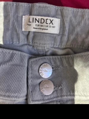 Ljusgrå manchesterbyxor Lindex - Säljer ett par ljusgrå manchesterbyxor från Lindex i storlek 164. Byxorna är flared, klassiska fickor och två silverfärgade knappar framtill. Tillverkade i mjuk manchester som ger en retro och chill vibe.