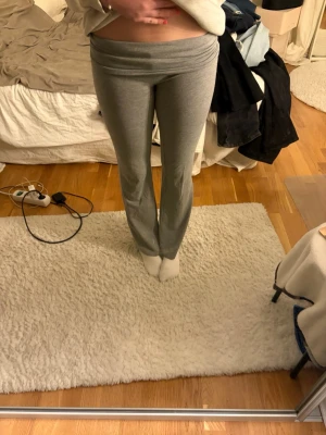 Grå bootcut leggings - Säljer ett par grå leggings med bootcut-modell och hög, viktbar midja. De är stretchiga och sitter tajt över låren men är utsvängda nedtill. Perfekta för en chill och trendig look. Materialet känns mjukt och bekvämt, troligen bomullsblandning.