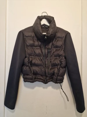 Svart pufferjacka från Zara - Svart pufferjacka från Zara med hög krage.  Ärmarna är i ett annat material vilket ger en cool kontrast. Liten I storleken så passar även S. 