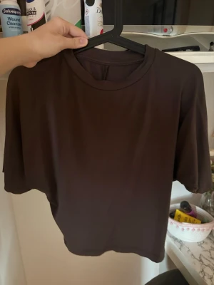 Brun basic t-shirt  - En enkel brun t-shirt med rund hals och korta ärmar. Tillverkad i mjuk bomull som känns skön mot huden. Perfekt att matcha med jeans eller shorts för en clean och avslappnad look, sitter tightare i midjan.