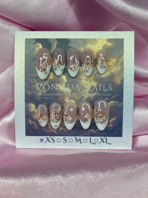 SoftSakura (XS);Medium Almond - Handgjorda press-on naglar i en elegant fransk design med nude bas, vita tippar och detaljerade sakura blommor samt små kristallstenar. Naglarna har en medium lång almondform och ger en lyxig och trendig look.XS: 14 mm, 11 mm, 11,5 mm, 10 mm, 8 mm 