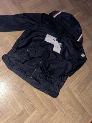 blå moncler windbreaker - säljer min snygga moncler windbreaker i en mörkblå färg jackan ör storlek s men passar även som m och köptes i november skicket på den är nästan som ny då jag kanppt kan se något fel i verkligheten anledningen jag säljer denna fina jackan är att jag helt enkelt växt ut den denna jackan passar perfekt för dig som vill sticka ut extra mycket där ute nu i sommaren priset kan diskuteras 