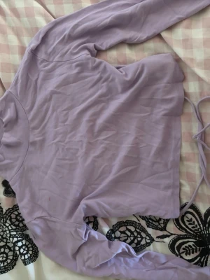 Ljuslila långärmad topp - Trendig ljuslila långärmad topp med croppad passform och knytband i ryggen utan rygg alltså. Perfekt för dig som gillar en enkel men snygg stil. Mjuk och skön känsla, passar till många olika outfits.