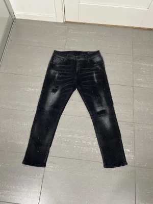 Svarta slim jeans från Dondup - W33 men sitter som 30/31. Nypris 3299. Jeansen är använda men i mycket bra skick, inga defekter.Snygga svarta skinny jeans från Dondup med slitningar och lätt tvättad look. Jeansen har klassisk femficksdesign, låg midja och smal passform. Perfekta för dig som gillar en trendig och avslappnad stil.