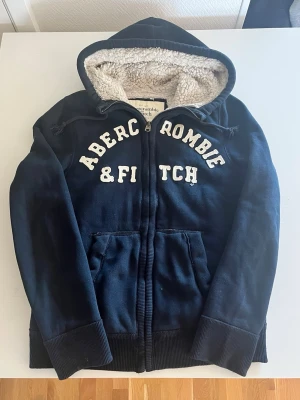 Abercrombie & fitch zip hoodie  - Riktigt snygg och sällsynt Abercrombie fodrad zip hoodie i mörkblå färg. Riktigt snygg och fint skick inga fel storlek L kan även passa M kan ta mätt vid behov. Endast 568 kr kom gärna med frågor och prisförslag 😁✌️ har även mer i min profil kolla gärna rabatt vid flera