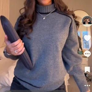 Grå stickad polotröja med svarta detaljer - Mysig grå stickad polotröja med svarta detaljer längs axlarna. Tröjan har ribbade muddar och hög krage, perfekt för kyliga dagar. Enkel och stilren design som passar till det mesta.