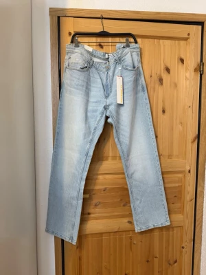 Ljusblå raka jeans  - Säljer ett par ljusblå jeans från Weekday med rak passform och klassisk femficksdesign. Jeansen har hög midja och är tillverkade i 100% bomull för en skön och avslappnad look. Perfekta till sneakers eller boots för en trendig vardagsstil.