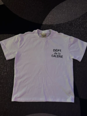 Gallery dept T shirt - Vit t-shirt från Gallery Dept med svart tryck 'DÉPT. de la GALERIE' på bröstet och i större format på ryggen. Klassisk passform och rund hals. Tillverkad i mjuk bomull för en skön känsla. Aldrig använd storlek S.