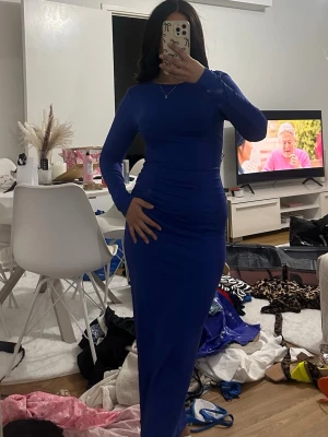 Långärmad blå långklänning - Säljer en stilren blå långklänning med lång ärm och figurnära passform. Klänningen har en enkel, elegant design utan synliga detaljer eller mönster och är perfekt för dig som gillar en klassisk look. Materialet känns mjukt och stretchigt. Sorlek S