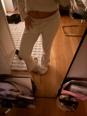 Vita ribbade mjukisbyxor med slits - Säljer ett par vita mjukisbyxor med ribbad struktur och slits nedan . Byxorna har raka ben och är supermjuka och sköna, perfekta för chill dagar hemma. Materialet ser ut att vara bomull eller en bomullsblandning.