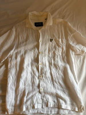 Vit linneskjorta från Lyle & Scott - Säljer en vit skjorta från Lyle & Scott i luftigt linne. Fräsch skjorta men behöver en strykning. Liten fläck vid knapp se bild