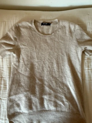 ❤️Beige stickad topp från Lisa Yang❤️ - Supermjuk beige  topp från Lisa Yang med rund halsringning och korta ärmar. Toppen har ribbade muddar vid ärmslut och nederkant, vilket ger en snygg och enkel look. Perfekt att styla med jeans eller kjol. I bra skick 