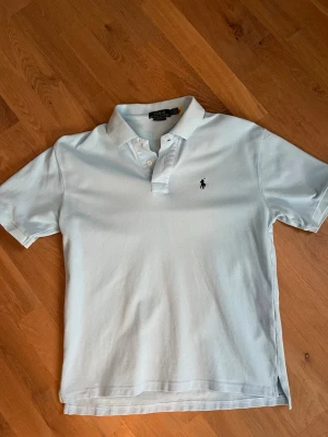 Ljusblå pikétröja från Ralph Lauren - Klassisk ljusblå pikétröja från Ralph Lauren i storlek M.