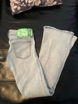 Ljusblå bootcut jeans Cheap Monday - Säljer ett par ljusblå bootcut jeans från Cheap Monday med klassisk femficksmodell och en grön logopatch bak.