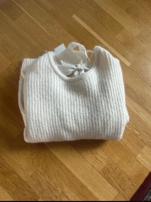 Stickad tröja - Jättefin mysig stickad tröja med rosett i ryggen. Bara använd en gång och i jättebra skick.