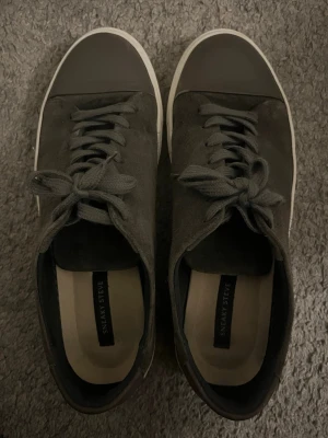 Mörkgråa sneakers från Sneaky Steve - Snygga mörkgråa sneakers från Sneaky Steve i mocka med vita sulor och matchande mörkgråa skosnören. Klassisk låg modell med rund tå och diskret design som passar till det mesta. Perfekta för dig som gillar stilrena och tidlösa skor.