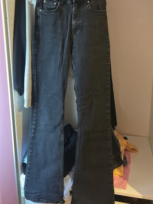 Svarta bootcut jeans från Gina - Säljer ett par svarta bootcut jeans från Gina i storlek 34. Jeansen har klassisk femficksmodell, hög midja och utsvängda ben. Materialet är mjukt denim med snygg tvättad look och silverfärgade detaljer. Perfekta för en trendig och avslappnad stil.