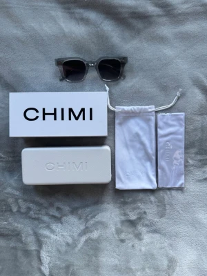 Grå CHIMI 04 helt nya - Säljer ett par stilrena solglasögon från CHIMI i grå design. Medföljer originalförpackning, hårt fodral och mjuk påse med CHIMI-logga. Perfekta för dig som vill ha en clean och modern look.