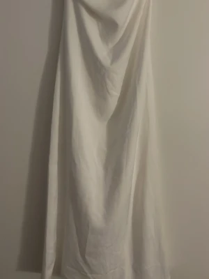 Vit långkjol i bomull - En fin vit klänning som har rak passform och en slits där bak som ger extra rörelsefrihet. Perfekt för sommarens varma dagar. Den är ny med prislapp. 