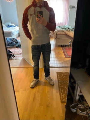 Grå och vinröd hoodie från Superdry - Säljer en snygg hoodie från Superdry i grått med vinröda ärmar och huva. Klassisk känguruficka framtill och dragsko i huvan. Broderad Superdry-logga på bröstet. Säljer den för att jag behöver pengar till sommaren 😔☝️.
