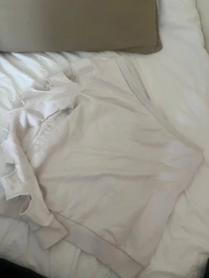 Ljusbeige off-shoulder sweatshirt med slitningar i armen  - Svincool ljusbeige sweatshirt från NAKD-AFJ i storlek S. Hoodien har slitningar i ärmen. Tillverkad i mjukt material som känns skönt mot huden. Perfekt för en avslappnad och chill stil.