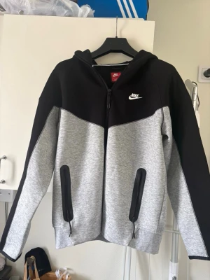 Grå svart nike tech  dress  - Säljer en grå svart nike tech dress (byxorna och tröjan)