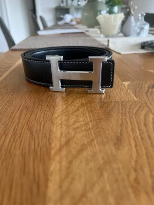 Svart skärp med H-spänne - Snyggt svart skärp med h spänne, perfekt överallt och enkel att styla. Använt ca 1 gång och inprincip nytt. Hör av er vid intresse. 