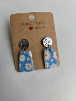 Handgjorda örhängen med prästkragemönster - Unika handgjorda örhängen med silverfärgade hamrade plattor och rektangulära hängen med prästkragemönster. Jättefina till midsommar! Tillverkade för hand av mig i polymerlera. 