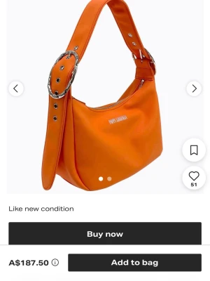 Orange axelremsväska från Poppy Lissiman - Snygg orange handväska från Poppy Lissiman med bred axelrem och stora silverfärgade spännen. Väskan har en mjuk, rundad form och är tillverkad i slätt konstläder. Loggan syns framtill i vitt. Perfekt för dig som vill sticka ut med färg. Helt ny o såklart oanvänd.