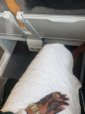 Vit spetskjol med volangkant - Säljer en vit kjol i spets med elastisk midja och volangkant. Kjolen har ett romantiskt mönster och är lätt och luftig, perfekt för sommardagar. Materialet känns mjukt och har en snygg struktur som ger kjolen extra karaktär.