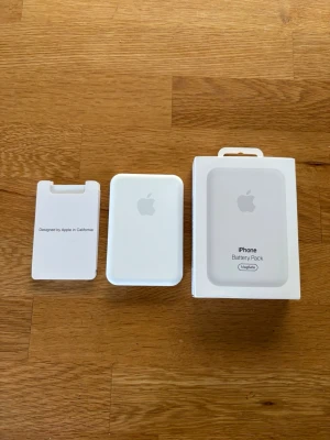 Apple MagSafe iPhone Battery Pack - Säljer ett vitt Apple MagSafe Battery Pack till iPhone. Batteripacket är kompakt, rektangulärt och har en slät yta med Apple-loggan på framsidan. Passar perfekt för trådlös laddning på språng och kommer med originalförpackning och insats.