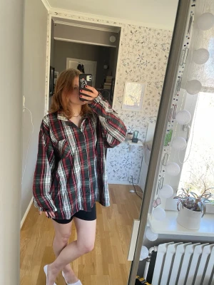 Oversized rutig skjorta i rött, grönt och vitt - Säljer en oversized rutig skjorta i rött, vitt och grönt. Skjortan har klassisk krage, långa ärmar och knappar framtill. Materialet känns som bomull och skjortan har en loose passform.