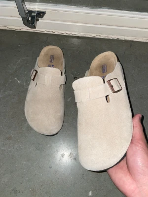 Beige Birkenstock Boston tofflor - Säljer ett par klassiska Birkenstock Boston tofflor i beige mocka. Dem är i nytt skick och passar bra nu när värmen har dykt fram. Skriv vid funderingar 