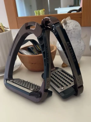 Bruna stigbyglar Acavallo AluPro - Säljer ett par bruna stigbyglar från Acavallo, modell AluPro. De är tillverkade i aluminium med svarta detaljer och har en greppvänlig platta i metall. Snygg och modern design som passar till ridning och ger bra stöd för foten. Är lite små repor på.