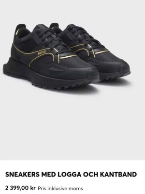 Svarta BOSS sneakers med gulddetaljer - Stilrena svarta sneakers från BOSS med snygga guldfärgade detaljer och logga på sidan. Skorna har en chunky sula, svarta skosnören och är tillverkade i en mix av läder och textil. Perfekta för dig som vill ha en modern och exklusiv look.