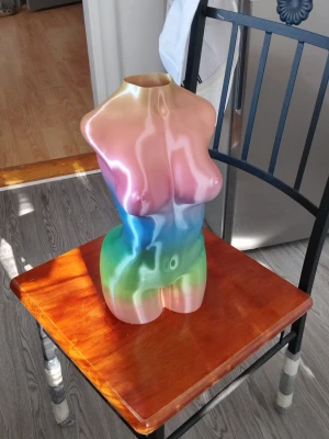 Regnbågsfärgad 40cm hög torso-dekoration - Unik dekorationsfigur 40cm hög i form av en kvinnlig torso med regnbågsfärgade nyanser i rosa, blått, grönt och gult. Tillverkad i ett slätt material, perfekt som konstnärlig inredningsdetalj eller samtalsstartare i hemmet.