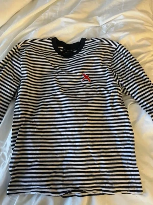 Randig långärmad tröja Axel Arigato - Säljer en svartvit randig långärmad topp från Axel Arigato med den broderade röda fågel loggan på bröstet. Den är perfekt nu när randigt blivit trendigt igen! Storlek: M. Priset kan diskuteras!