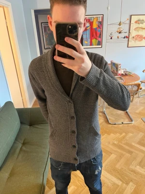 Cardigan hollister S - Mörkgrå stickad kofta med grov struktur och knappar framtill. Koftan har två fickor och bred krage, perfekt för lager-på-lager. Långärmad och ribbade muddar vid ärmslut och nederkant. Passar dig som gillar en avslappnad och stilren look.
