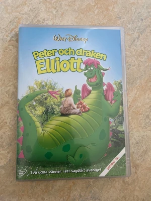 Peter och draken Elliott DVD - DVD-film med svensk tal av Disney: Peter och draken Elliott. Omslaget är färgglatt med illustration av en grön drake och en pojke. Filmen är en musikalisk familjeäventyrsklassiker och innehåller både tecknade och riktiga skådespelare.