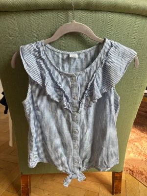Randig blus med volang och knyt - Blåvit randig blus med knyt och volanger från Lindex. Storlek 158/164
