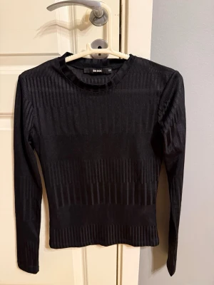 Svart ribbad topp från Bik Bok - Snygg svart långärmad topp från Bik Bok med ribbat material. Storlek XS, använd cirka 5 gånger.