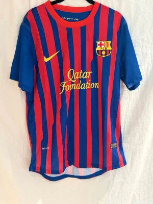Barcelona 11/12 Xavi #6 - Säljer Barcelona hemmatröja 2011/12 med Xavi #6 på ryggen.  Från en av Barcas absolut bästa eror där Xavi styrde mittfältet tillsammans med spelare som Andrés Iniesta och Lionel Messi.  Nike-loggan och Barca-emblemet är tryckta (inte broderade), vilket ger en lättare och mer matchlik känsla.  Riktigt clean tröja med stark koppling till tiki-taka-eran.