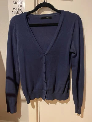 Mörkblå kofta från Vero Moda - Snygg mörkblå kofta från Vero Moda med v-ringning och knäppning framtill. Långärmad modell i mjukt och tunt material, perfekt att slänga över en topp eller t-shirt. Enkel och stilren design som passar till det mesta. Skickar helst med PostNord😁