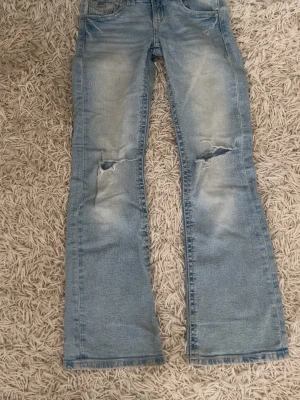Ljusblå slitna bootcut jeans Ginatricot - OBS! Har haft hål i rumpan som syts igen! Säljer ett par ljusblå bootcut jeans från Ginatricot med slitningar och hål på knäna. Jeansen har klassisk femficksmodell, knappgylf och är tillverkade i denim. Perfekta för en avslappnad och trendig look.
