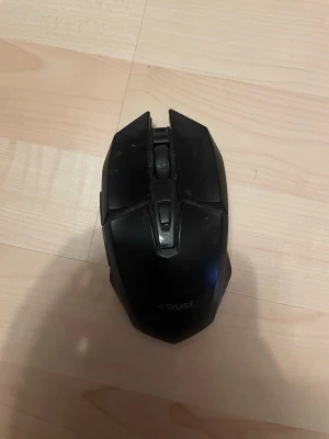 Svart gamingmus från Trust - Säljer en svart gamingmus från Trust med en futuristisk design och flera knappar. Musen har en matt finish och greppvänliga sidor i plast. Perfekt för gaming eller vardagsbruk vid datorn.