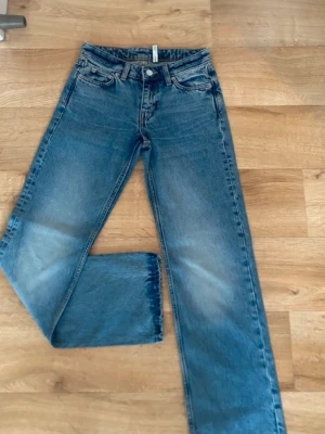 Jeans - Säljer ett par klassiska blå jeans från Weekday med rak passform och fem fickor. Jeansen har en snygg tvätt med ljusa partier på låren och är tillverkade i denim. Perfekta för dig som gillar en enkel och tidlös look.