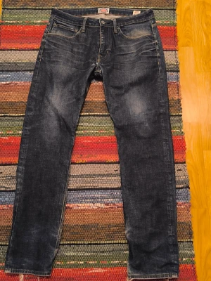 Crocker blåa jeans, storlek W33 L32 - Jeans från Crocker i modellen 341 Regular Straight. Byxorna har dragkedja och knappgylf framtill. De har två framfickor, en liten myntficka och två bakfickor. Midjan är normalhög och passformen är rak. Skönt raggarslitna. Se bilder.