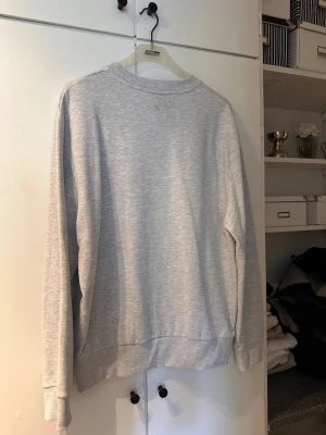 Ljusgrå basic sweatshirt - En stilren ljusgrå sweatshirt med rund hals och ribbade muddar vid ärmslut och nederkant. Tröjan är enkel och passar perfekt till ett avslappnat streetwear-utseende. Tillverkad i mjukt material för maximal komfort.