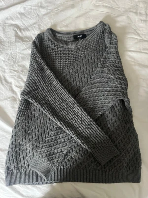 Grå stickad tröja från Object - Snygg grå stickad tröja från Object med coolt strukturerat mönster och rund halsringning. Tröjan har långa ärmar och ribbade muddar vid ärmslut och nederkant. Perfekt för lager-på-lager och chill dagar.