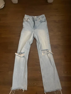 Ljusblå slitna jeans från Zara - Ljusblå jeans från Zara med utsvängda ben, slitningar och hål vid knäna. Dom har hög midja och långa ben. 